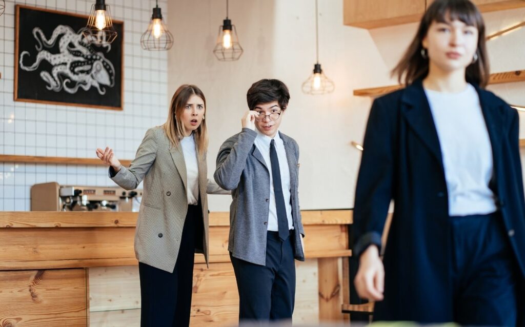 seorang pekerja perempuan dan laki-laki sedang bergosip kepada salah satu karyawan di tempat kerjanya merupakan bentuk diskriminasi di tempat kerja