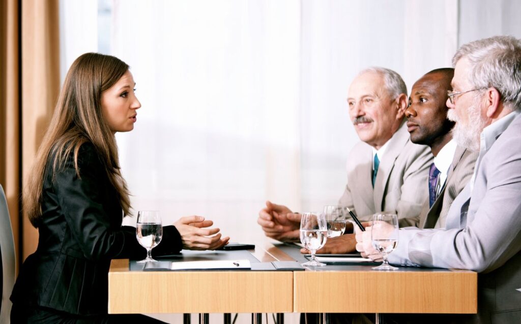 a woman wear black suit with brown hair is negotiating salary during job interview