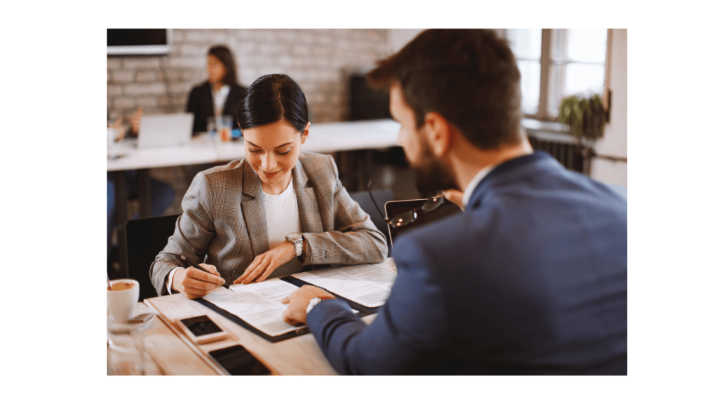 A woman wearing a brown suit is signing the employment contract in front of the recruiter at the office