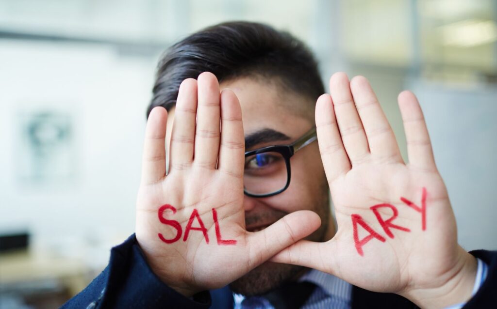 seorang pria menggunakan kacamata hitam dengan menunjukkan telapak tangannya yang bertuliskan negosiasi gaji