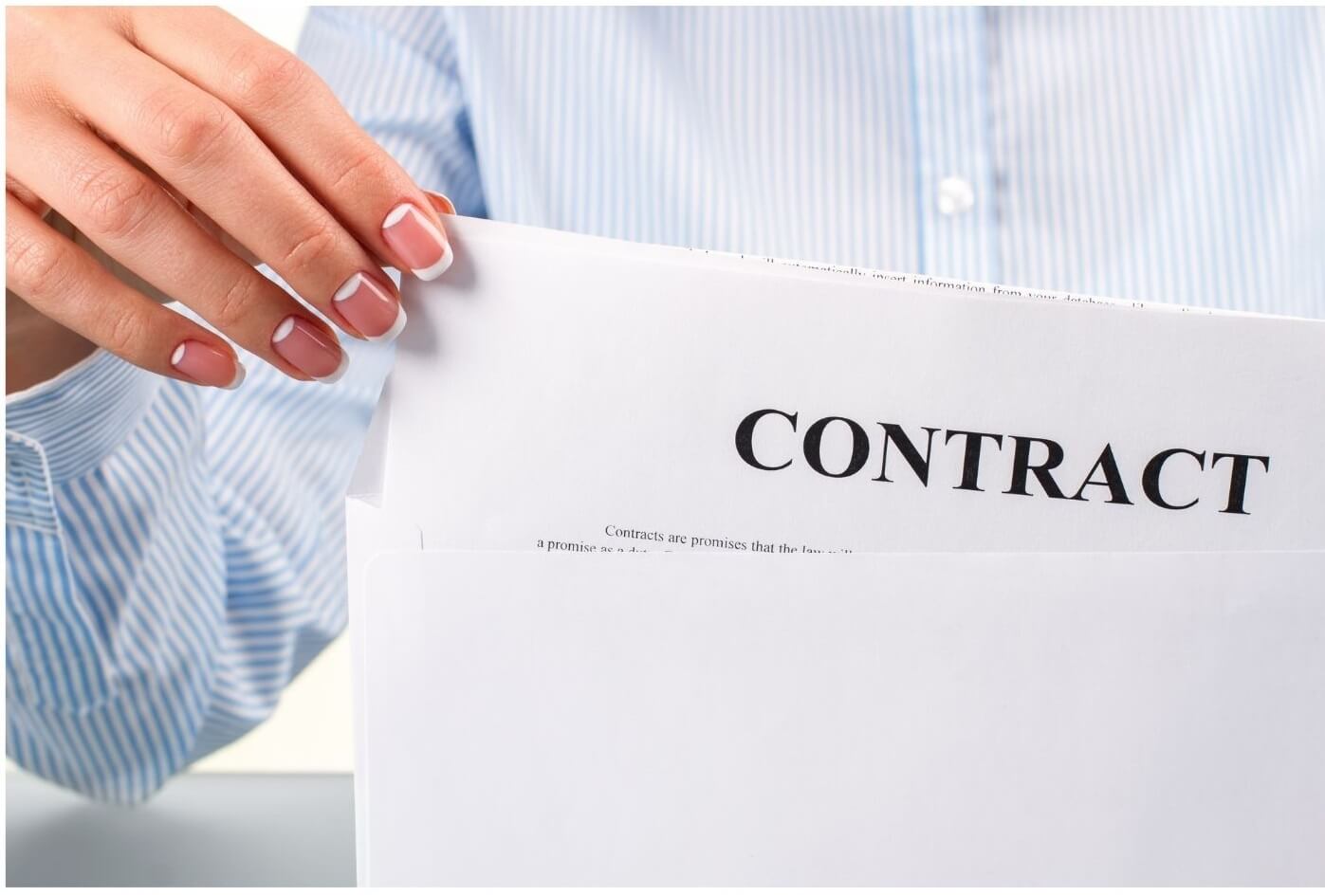 A woman with french nails manicure wearing a stripes pattern shirt takes the employee contract letter from a white envelope