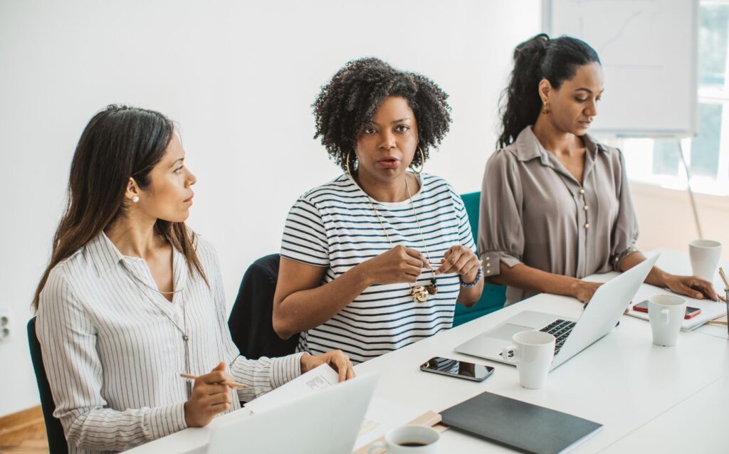 a woman wearing a black and white striped shirt is decline a job offer through a meeting in her office